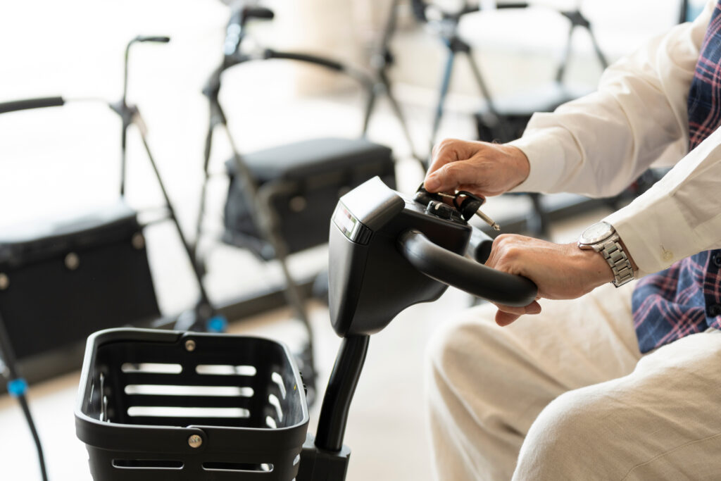 Gros plan de mains posé sur le guidon d'un scooter pour personne à mobilité réduite