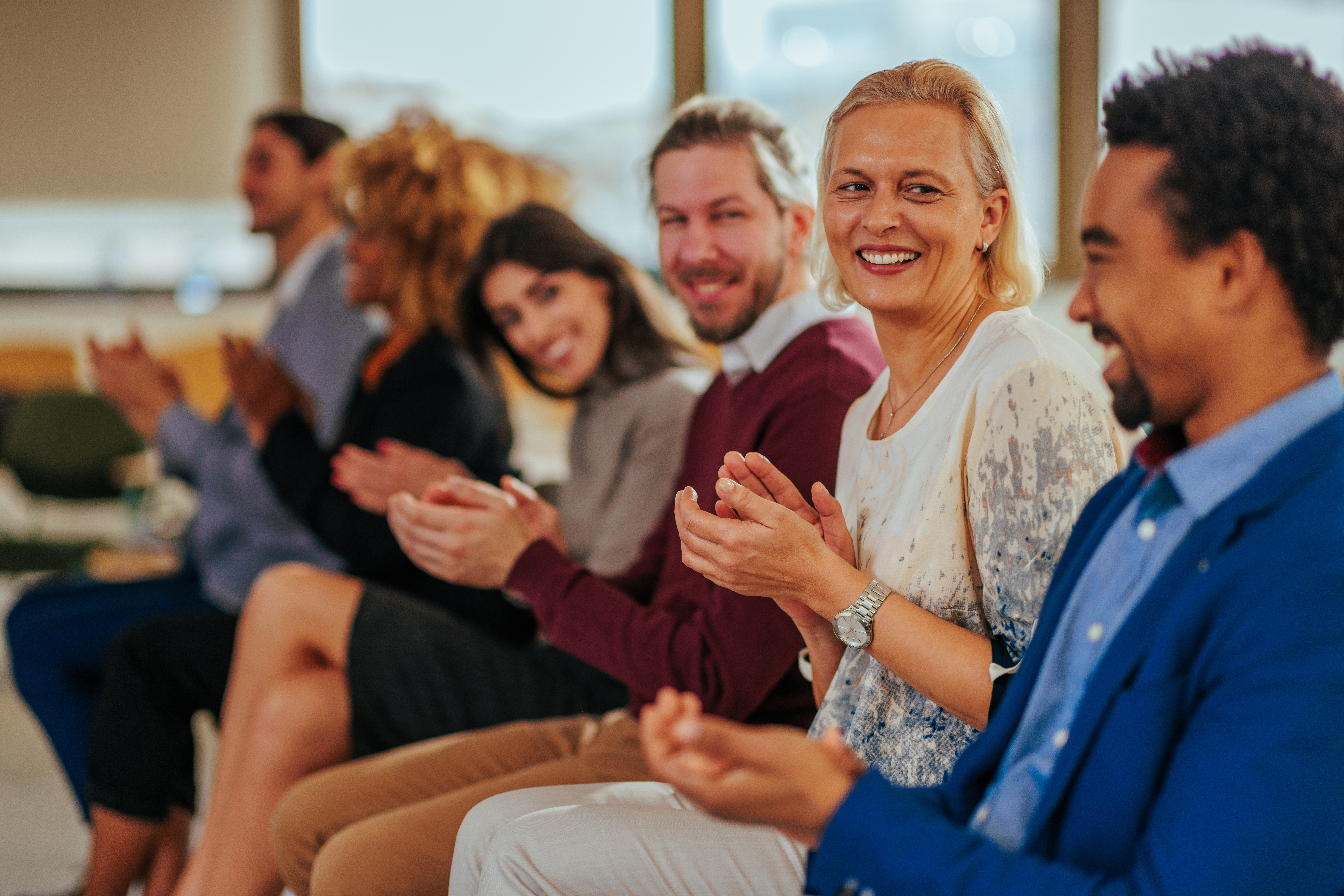 Pendant un rassemblement, une rangée de personnes souriant et applaudissant