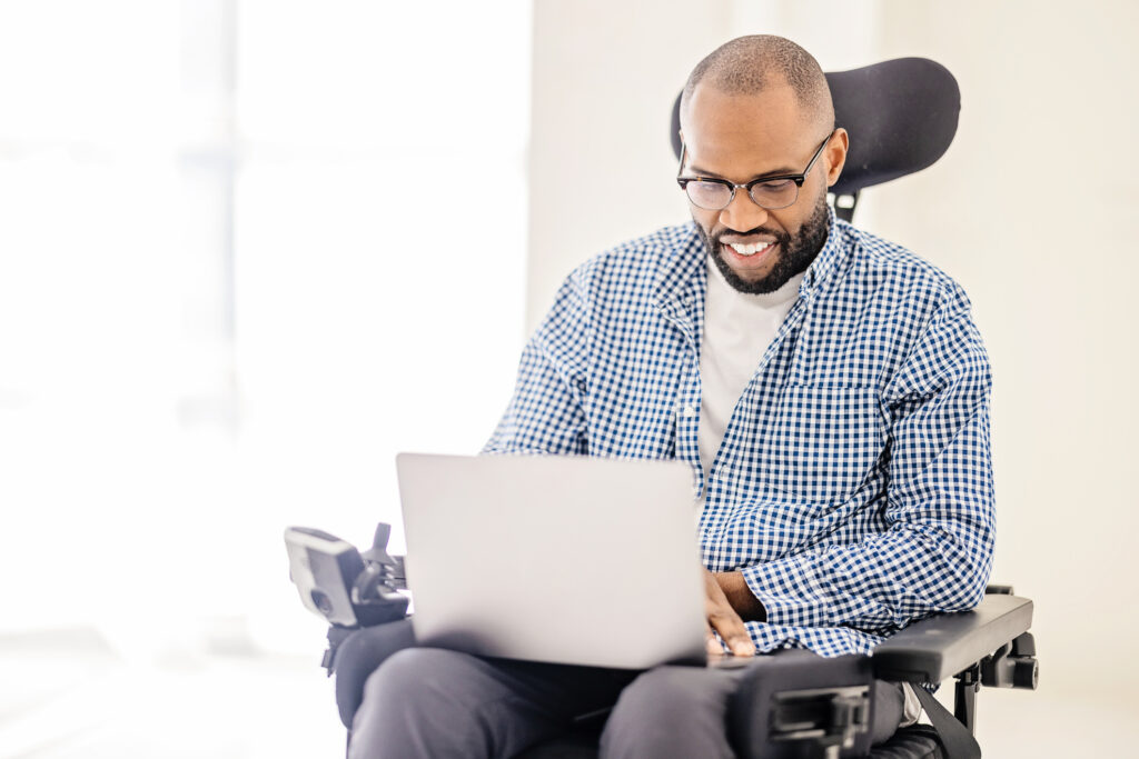 Un homme en fauteuil roulant consulte son ordinateur portable