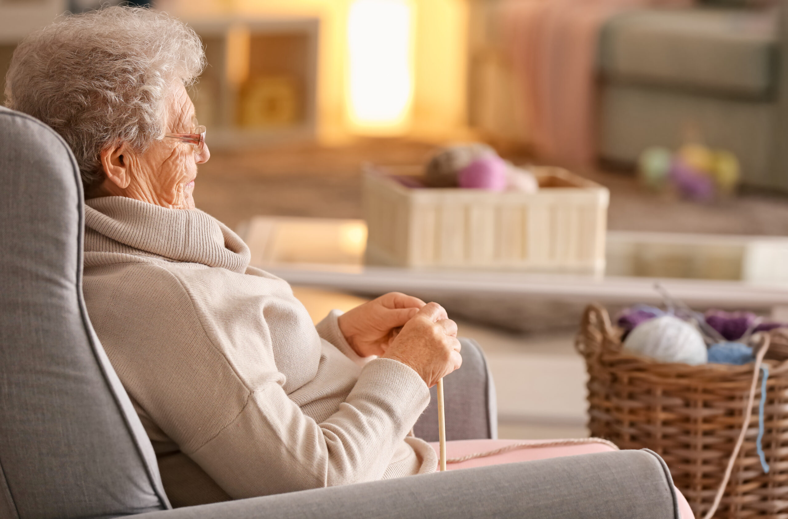 Une femme âgée fait du tricot dans son salon