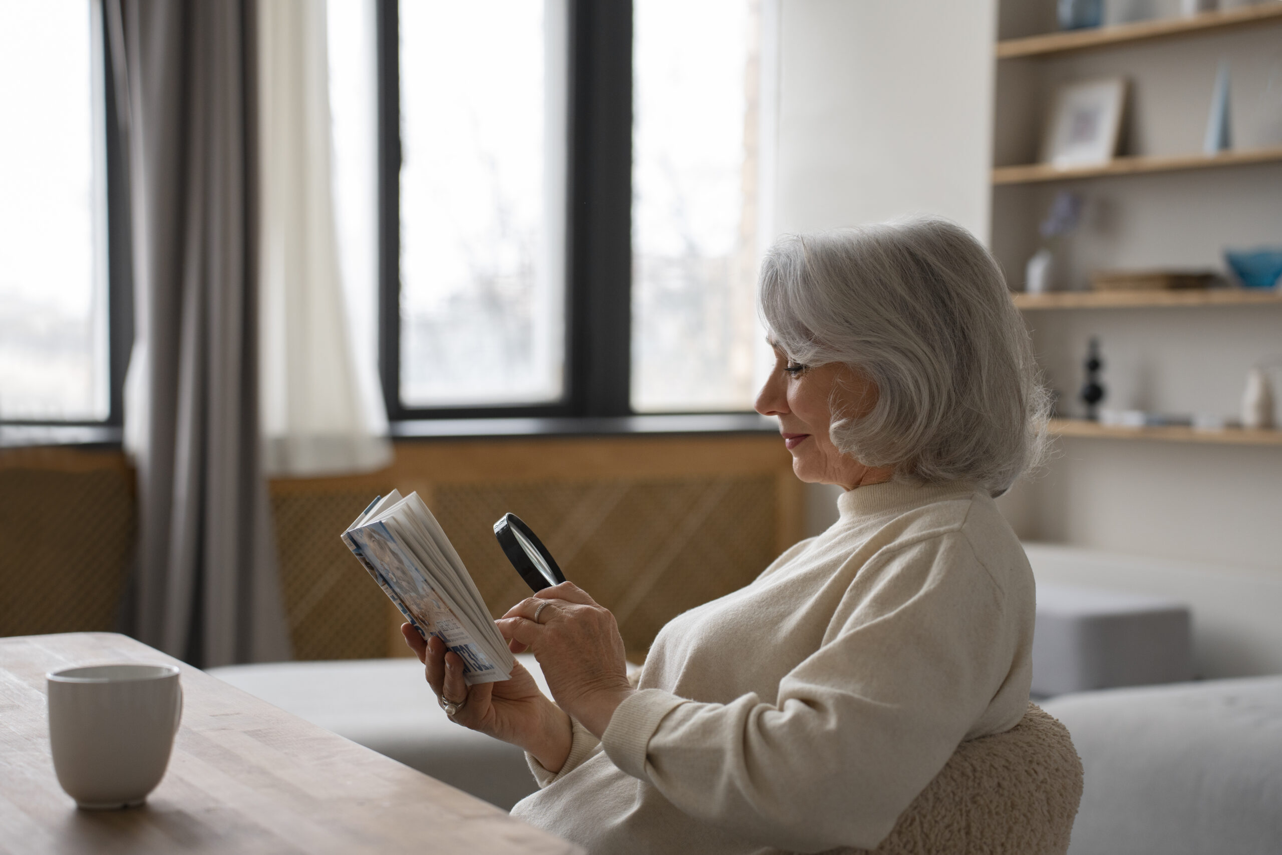 Une femme âgée lit un livre à l'aide d'une loupe