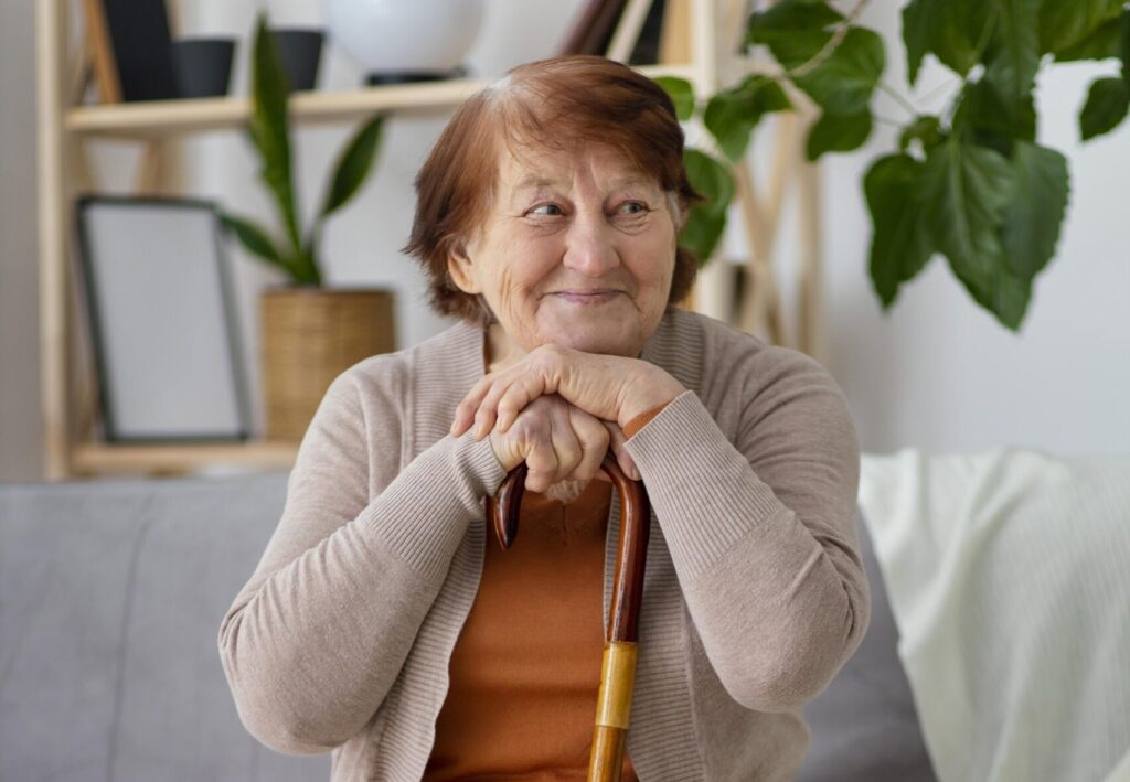 Une femme avec une canne assise sur un canapé