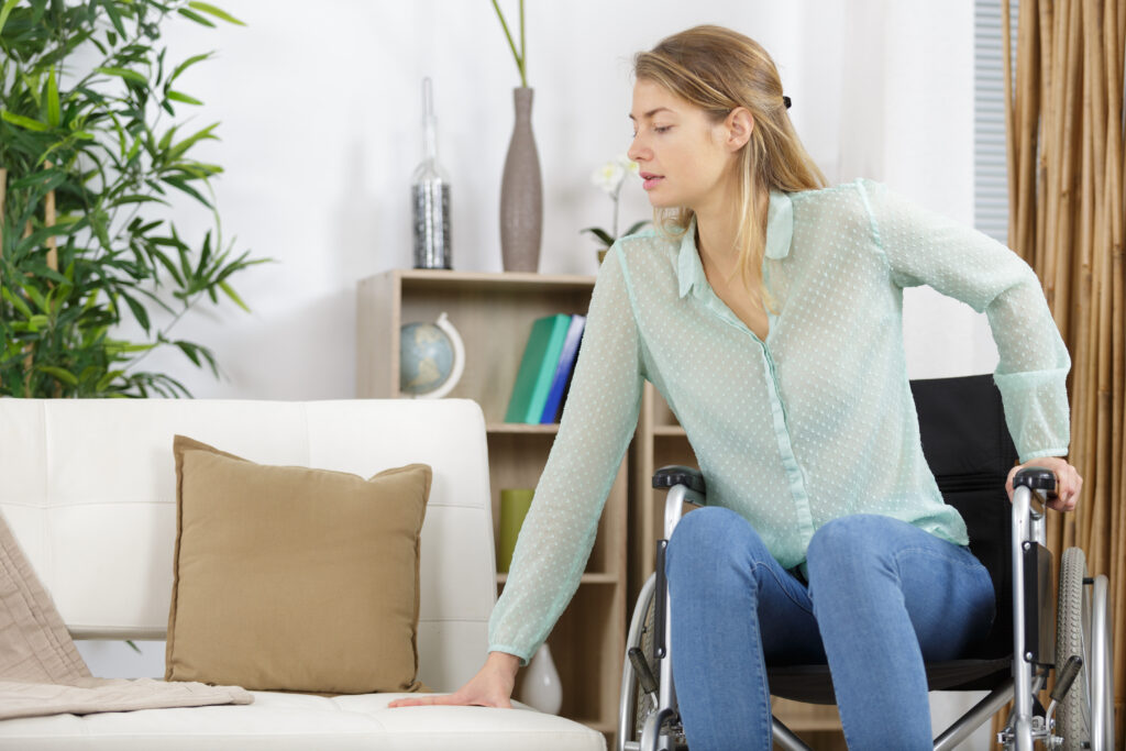 Un femme en train de passer de son fauteuil roulant à son canapé