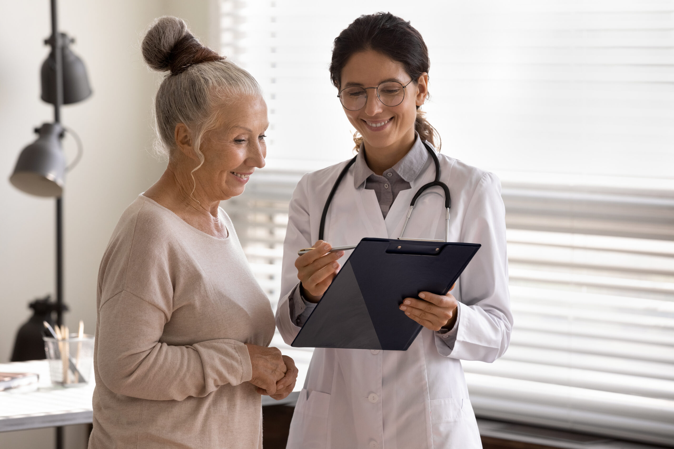 Une femme médecin montre un bilan à sa patiente âgée, elles sourient