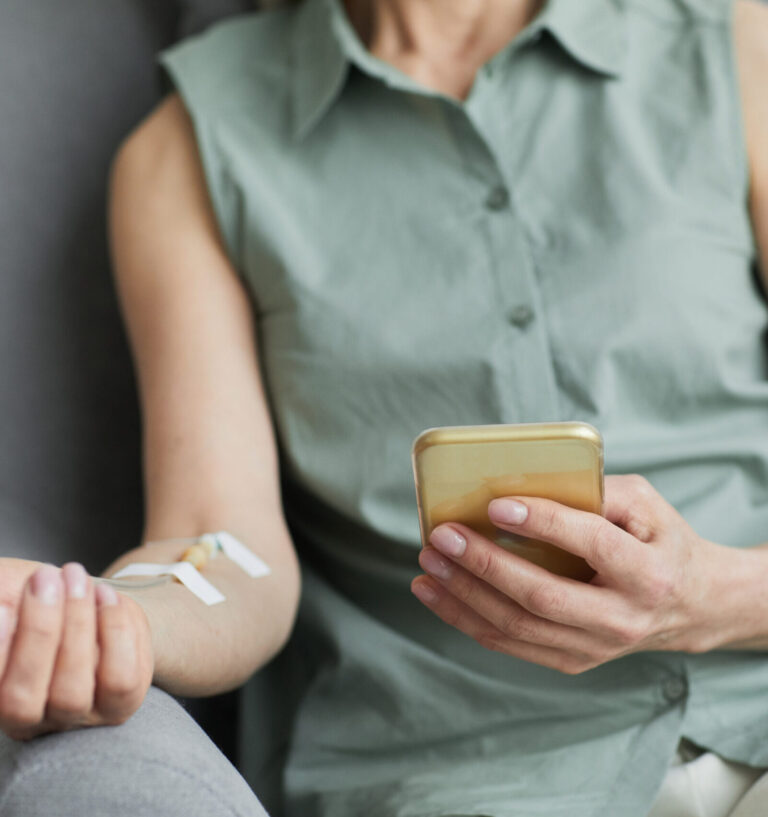 Une femme sous perfusion consulte son smartphone