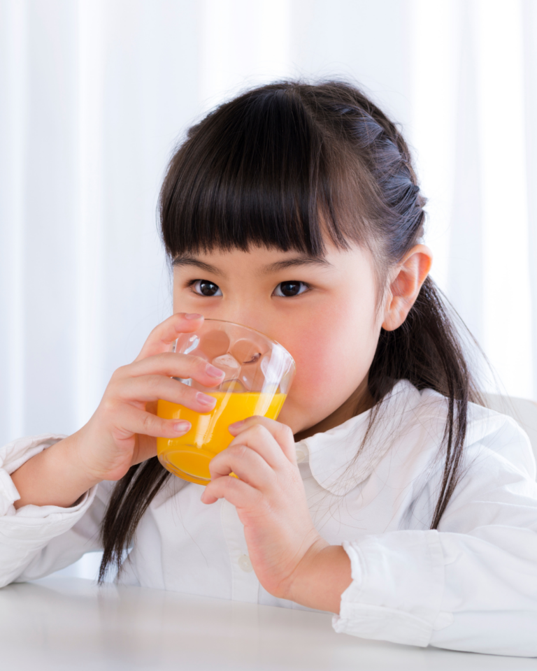 Une jeune fille boit un jus d'orange