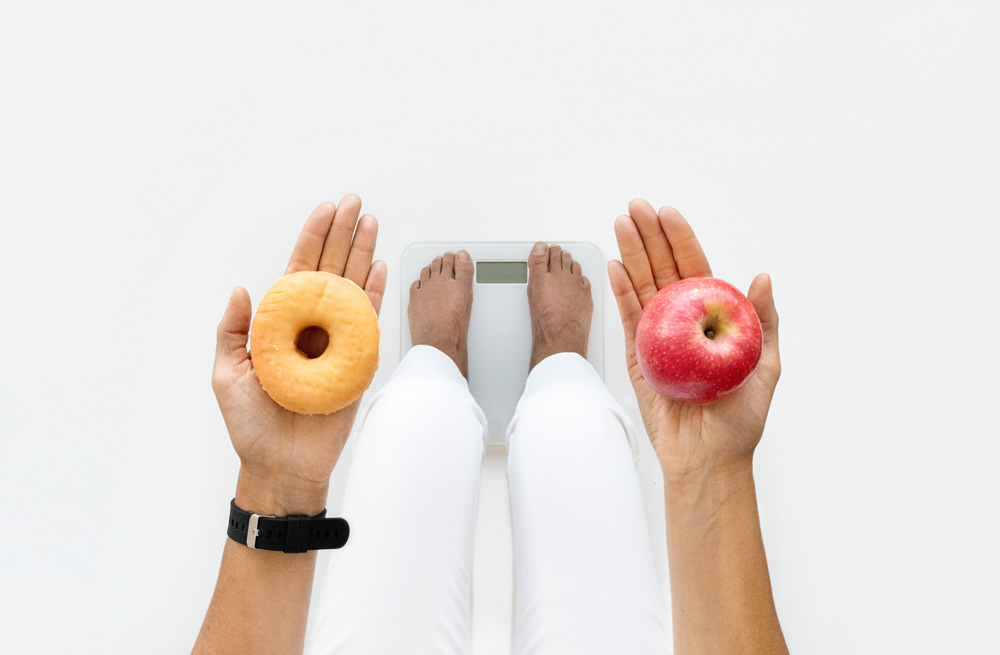 femme debout sur une balance tenant un beignet et une pomme